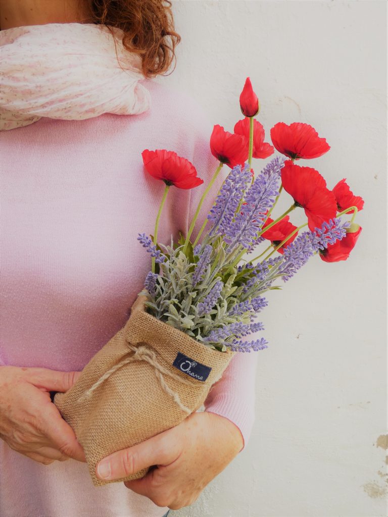 Mujer sujetando un saco lleno de lavandas artificiales y amapolas de seda