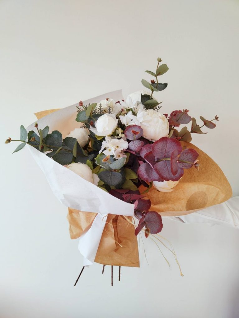 Ramo de peonias blancas y eucaliptos artificiales de aspecto natural envuelto en papel kraft