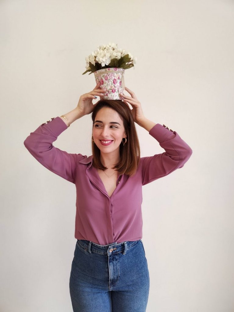 Mujer sujetando con sus manos sobre su cabeza, el Cubo Lily, un cubo forrado en tela de flores con hortensias artificiales en tono crema.