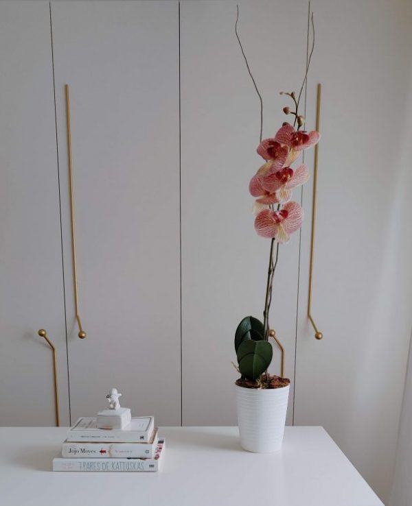 Orquídea Artificial en tono fucsia colocada en una maceta blanca.